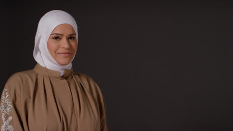 Studioporträt-Einer-Lächelnden-Muslimischen-Frau-Mit-Hijab-Vor-Schlichtem,-Dunklem-Hintergrund-2